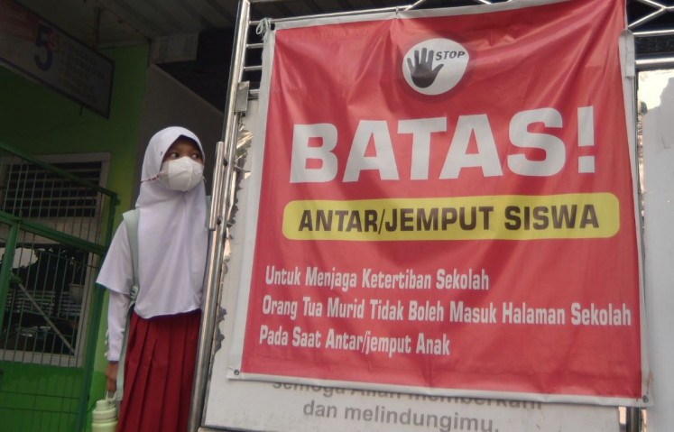 Murky schooling: A schoolgirl waits to be picked up on Sept. 16, 2026 next to a sign on drop-off/pickup rules at a school in Padang, after classes were let out early as West Sumatra&rsquo;s provincial capital reinstated remote learning in response to a spike in the air pollutant standards index (ISPU) to 900 due to dense haze.