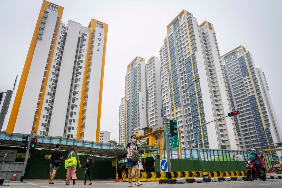 A woman wearing a face mask crosses a street in front of government public housing apartments in Singapore on October 17, 2026, as the country continues to be shrouded in haze caused by fires in Indonesia.