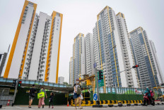 A woman wearing a face mask crosses a street in front of government public housing apartments in Singapore on October 17, 2026, as the country continues to be shrouded in haze caused by fires in Indonesia.