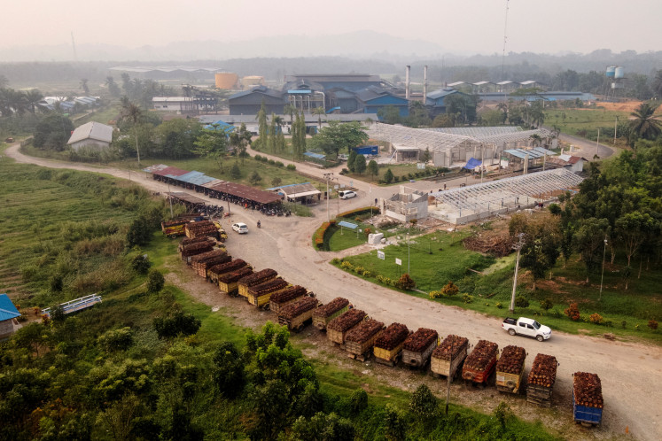 A drone view shows trucks loaded with oil palm fruit bunches waiting outside the Multi Prima Entakai (MPE) palm oil mill in Sanggau, West Kalimantan, October 2, 2026. 