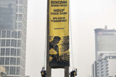 Greenpeace Indonesia activists unfurl a protest banner on Oct. 20 atop the Welcome Statue (Patung Selamat Datang) at the Hotel Indonesia traffic circle in Menteng, Central Jakarta.