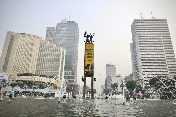 Greenpeace Indonesia activists unfurl a pair of giant banners on the Welcome Statue on Oct. 20, 2026, during a demonstration at the Hotel Indonesia traffic circle in Central Jakarta.