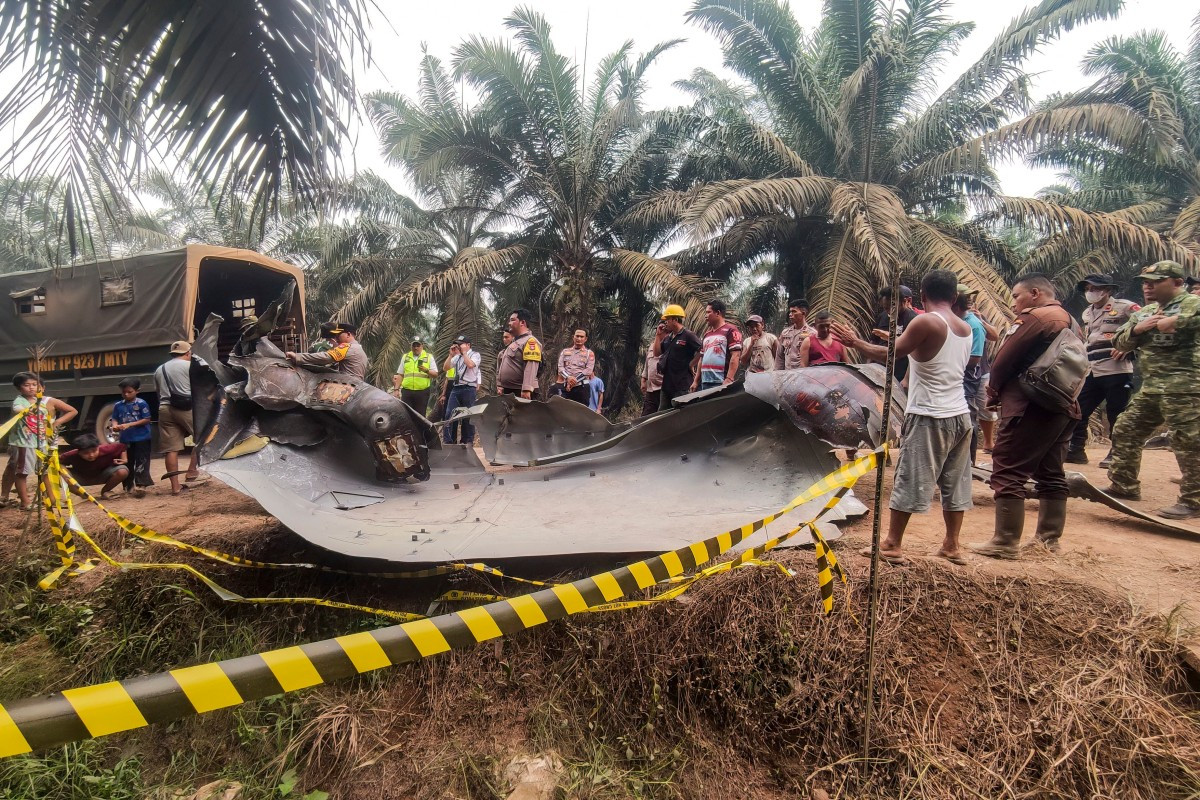 This picture taken on October 19, 2026 shows residents, plantation workers, and security officials gather around a large charred metallic fragment, suspected to be rocket debris, at an oil palm plantation in East Kotawaringin, Central Kalimantan. 