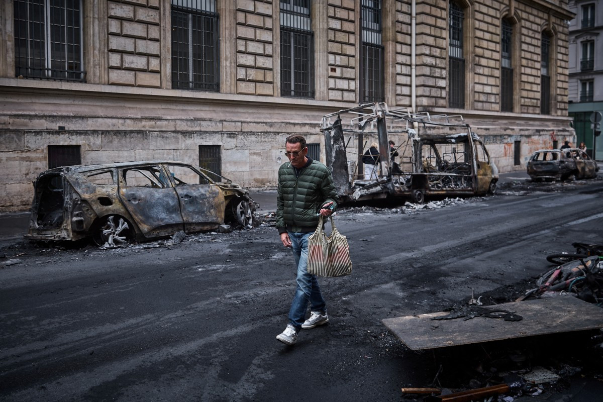 A man walks past a row of burnt out vehicles on Rue Yves Toudic destroyed after a nationwide protest against the &ldquo;high cost of living&ldquo;, in central Paris on October 19, 2026. 