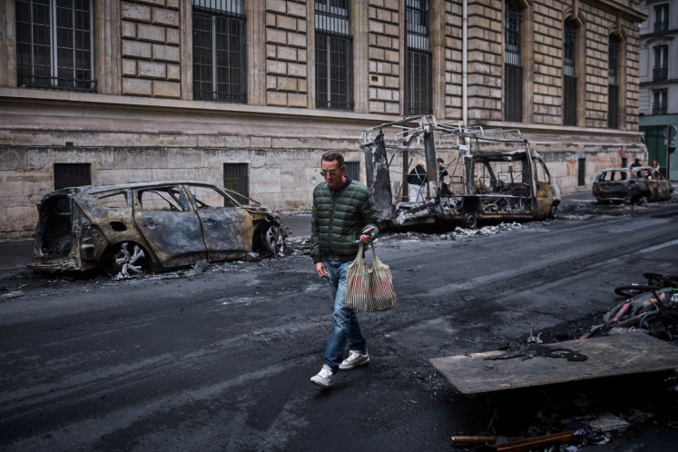 A man walks past a row of burnt out vehicles on Rue Yves Toudic destroyed after a nationwide protest against the &ldquo;high cost of living&ldquo;, in central Paris on October 19, 2026. 