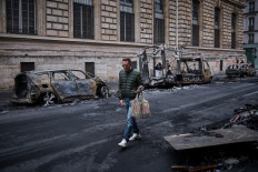 A man walks past a row of burnt out vehicles on Rue Yves Toudic destroyed after a nationwide protest against the &ldquo;high cost of living&ldquo;, in central Paris on October 19, 2026. 