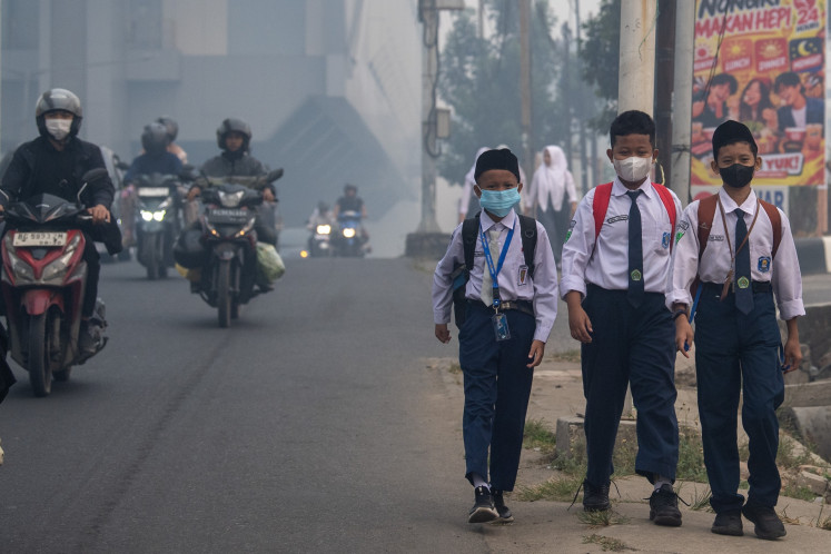 School students wear mask while walking on the street in Palembang, South Sumatra as the city is hit by haze from forest and peatland fire.