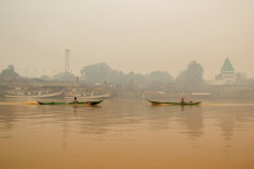 People ride wooden boats on the Kahayan River on Sunday as haze from forest and peatland fires shrouds Palangka Raya, Central Kalimantan.