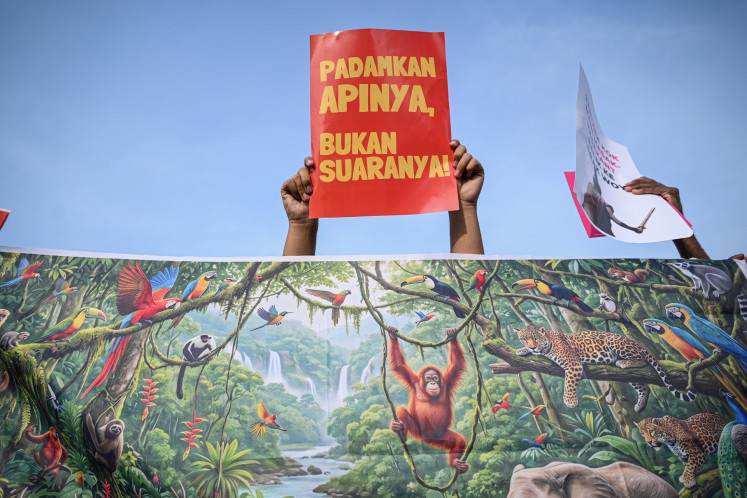 A protester holds a banner that reads &ldquo;Put out the fire, not people's voice!&ldquo; during a demonstration marking the second anniversary of President Prabowo Subianto and Vice President Gibran Rakabuming Raka's administration at the Tugu Tani monument in Central Jakarta on Oct. 20, 2026. 