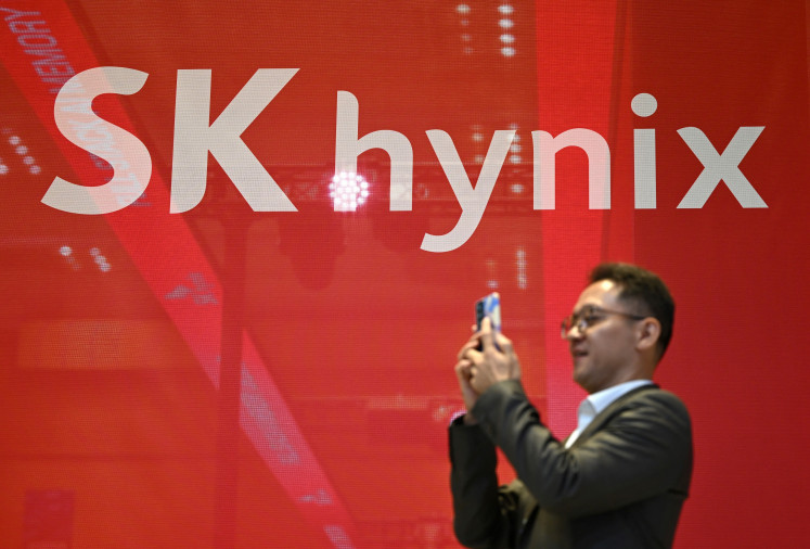 A man uses his phone to take a picture in front of the logo of SK hynix during a semiconductor exhibition at the COEX convention and exhibition center in Seoul on Oct. 14, 2026.