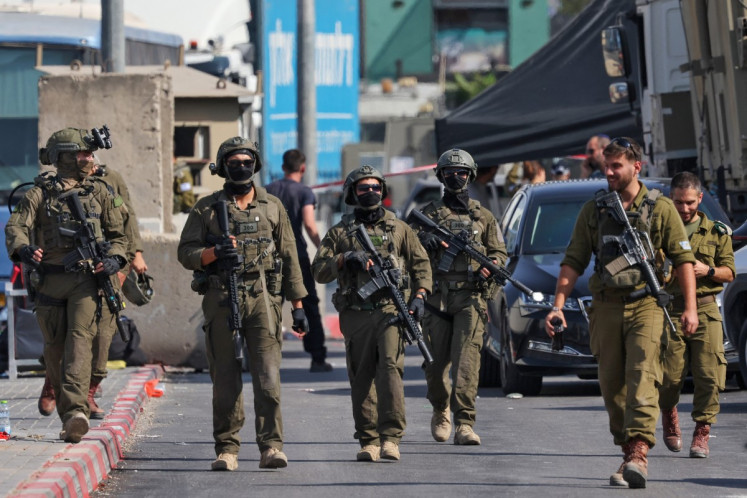 Israeli soldiers gather at the scene of an earlier fire exchange between armed Palestinians and Israeli forces following an incident at the norther checkpoint of Hebron in the Israeli-occupied West Bank on Oct. 23, 2026. Israeli troops on Oct. 23 shot dead two suspected Palestinian assailants in the West Bank after a shooting that left at least five people wounded, officials said.