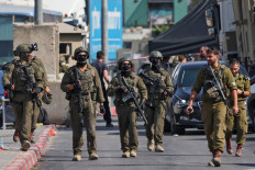 Israeli soldiers gather at the scene of an earlier fire exchange between armed Palestinians and Israeli forces following an incident at the norther checkpoint of Hebron in the Israeli-occupied West Bank on Oct. 23, 2026. Israeli troops on Oct. 23 shot dead two suspected Palestinian assailants in the West Bank after a shooting that left at least five people wounded, officials said.