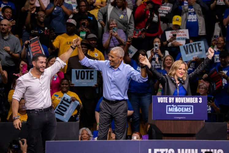 Former US President Barack Obama (center), Democrat Michigan senatorial candidate Abdul El-Sayed (left) and Michigan Secretary of State and Democrat gubernatorial candidate Jocelyn Benson (right) raise joined hands as they campaign together with other Michigan Democratics at a rally in Detroit, Michigan on October 24, 2026. 
