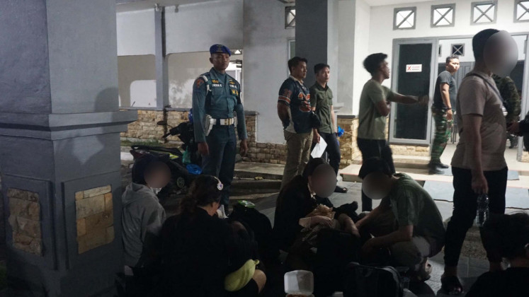 A Navy Military Police officer (standing left) watches over Vietnamese nationals detained over immigration violations on Tuesday at the Naval Regional Command (Kodaeral) IV/Batam in Batam city, Riau Islands. The Vietnamese, consisting of seven women and five men, were were detained after they attempted to leave Indonesia without crossing at an immigration checkpoint.