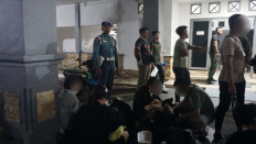 A Navy Military Police officer (standing left) watches over Vietnamese nationals detained over immigration violations on Tuesday at the Naval Regional Command (Kodaeral) IV/Batam in Batam city, Riau Islands. The Vietnamese, consisting of seven women and five men, were were detained after they attempted to leave Indonesia without crossing at an immigration checkpoint.
