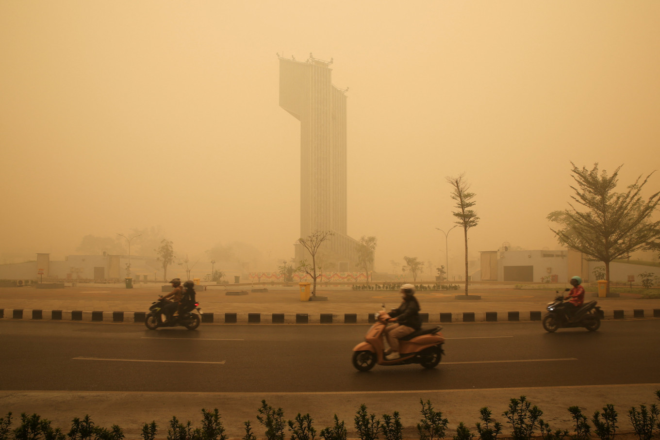 Motorcyclists wearing protective masks drive through the Talawang traffic circle as haze from wildfires shrouds the area in Palangka Raya, Central Kalimantan, on Oct. 24, 2026.