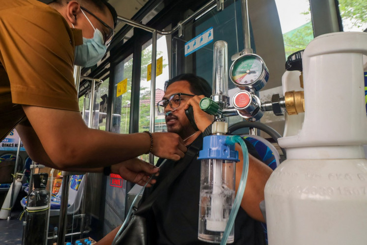 A health worker assists a resident receiving oxygen inside a mobile health service bus operated by the Palangka Raya city administration following respiratory issues caused by land and forest fires in Palangka Raya, Central Kalimantan, on October 26, 2026. More than 11,000 people have been treated for respiratory infections in Palangka Raya during a months-long wildfire crisis that has also affected Indonesia's neighbors with toxic haze pollution. 