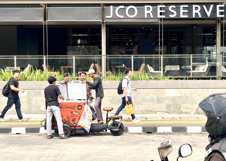 Coffee on the go: Workers buy iced coffee from a mobile vendor near an office building on Jl. M.H. Thamrin in Central Jakarta on Oct. 22, 2026. Mobile coffee stalls offer an affordable caffeine fix, with prices ranging from Rp 5,000 (28 US cents) to Rp 20,000 per cup.
