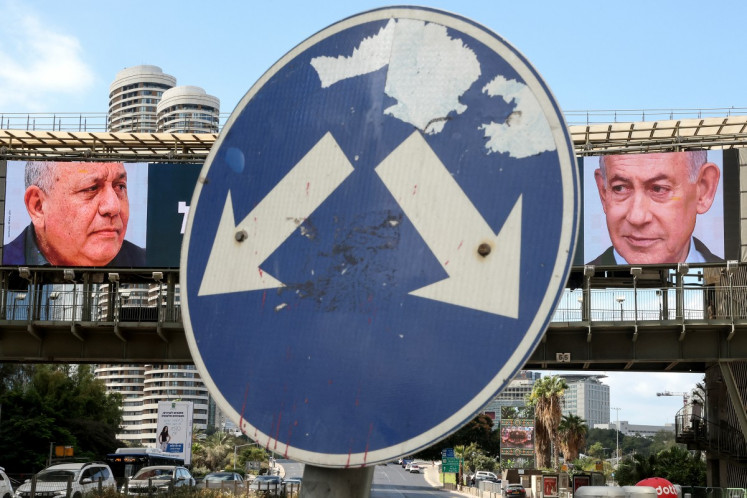 A road sign stands in front of a large billboard featuring Israel's Prime Minister Benjamin Netanyahu (right) of the Likud party and former military chief and leader of the centrist Yashar party, Gadi Eisenkot, in Ramat Gan on October 20, 2026.