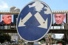 A road sign stands in front of a large billboard featuring Israel's Prime Minister Benjamin Netanyahu (right) of the Likud party and former military chief and leader of the centrist Yashar party, Gadi Eisenkot, in Ramat Gan on October 20, 2026.