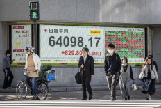 People walk past an electronic quotation board displaying the Nikkei Stock Average on the Tokyo Stock Exchange in Tokyo on Oct. 28, 2026.