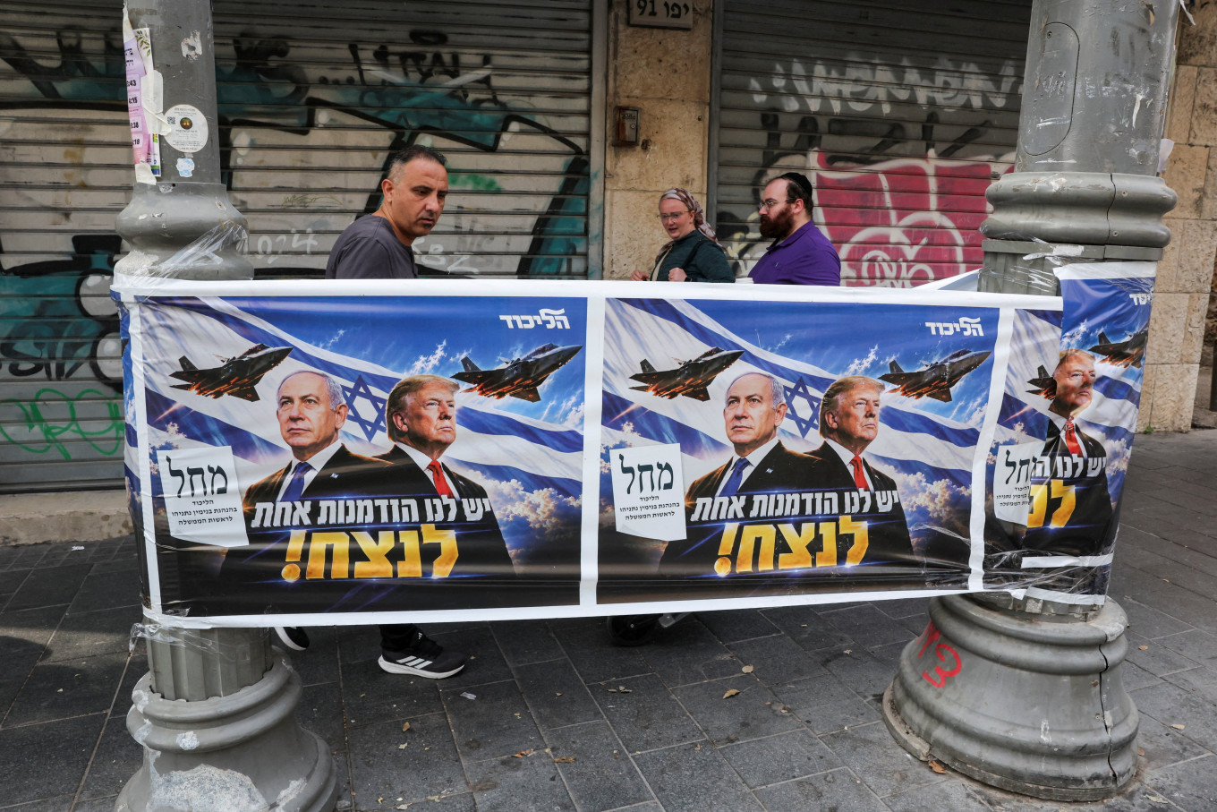 People walk past a poster of Israeli Prime Minister and Likud party leader Benjamin Netanyahu and US President Donald Trump during the country's national elections in central Jerusalem, October 27, 2026.