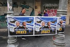 People walk past a poster of Israeli Prime Minister and Likud party leader Benjamin Netanyahu and US President Donald Trump during the country's national elections in central Jerusalem, October 27, 2026.
