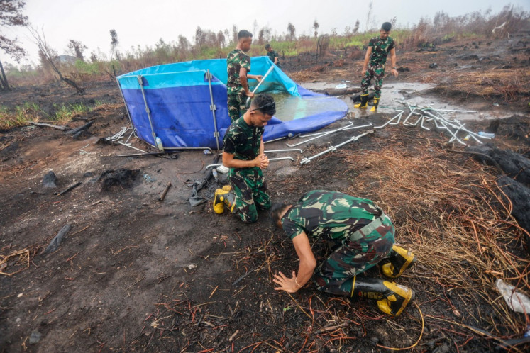 Indonesian soldiers, tasked with fighting forest and land fires, celebrate as it rains in Banjar Baru, South Kalimantan, on October 28, 2026, following months of forest and land fires. 