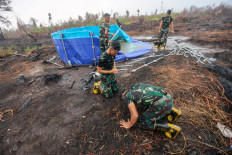Soldiers, tasked with fighting forest and land fires, celebrate as it rains in Banjar Baru, South Kalimantan, on October 28, 2026, following months of forest and land fires. 