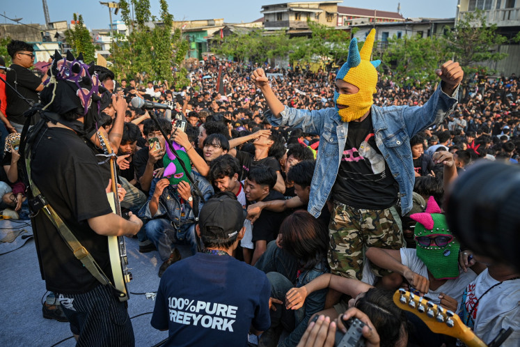 Concertgoers dance during punk band Dongker's performance at Plaza Kalibaru in Cilincing, North Jakarta on Oct. 10, 2026. For the performance, the band charged attendants 2 kilograms of rice and a book.