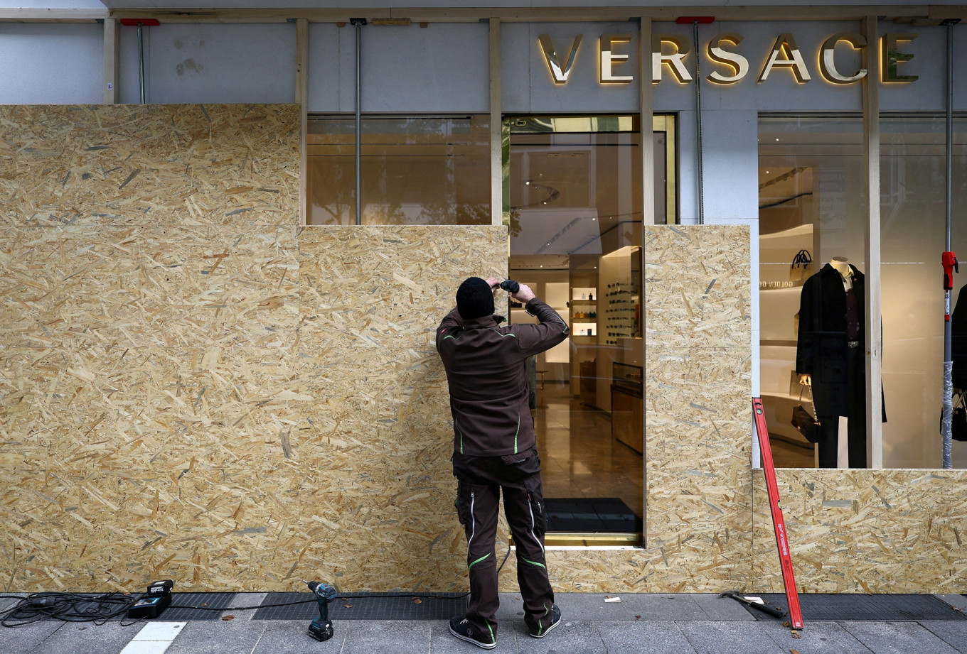 A worker secures a Versace store with wooden boards ahead of expected protests by the youth movement &ldquo;Gen Z regelt&ldquo; in Frankfurt, Germany, on Oct. 30, 2026.