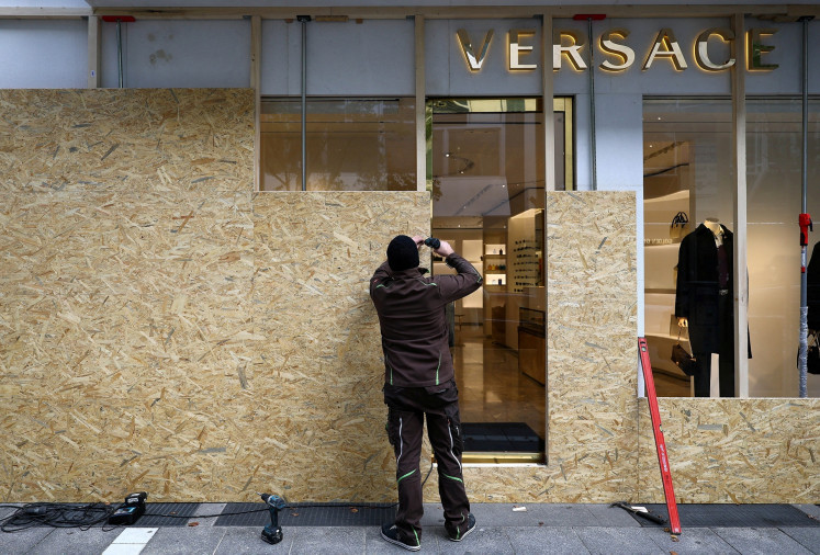 A worker secures a Versace store with wooden boards ahead of expected protests by the youth movement &ldquo;Gen Z regelt&ldquo; in Frankfurt, Germany, on Oct. 30, 2026.